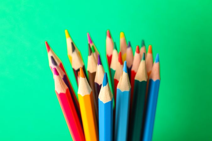 Multicolored pencils against green background, closeup