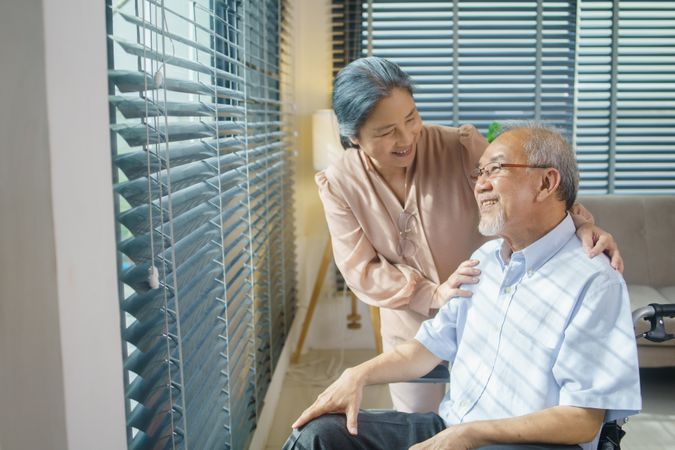 Older Asian woman takes care of husband sitting in wheelchair