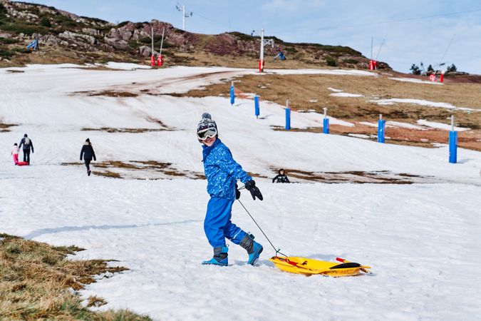 Boy with sledge walking on snowy slope