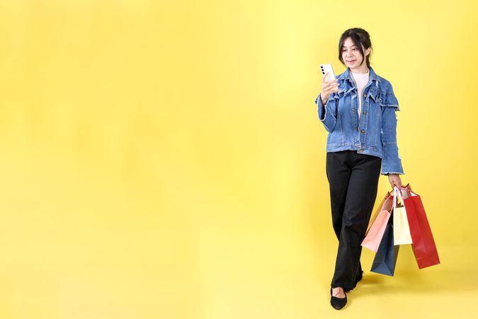 Indonesian Young Woman Holding Various Paper Bag and Cell Phone, Online Shopping Concept.