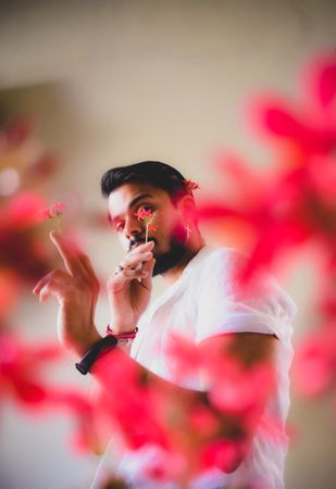 Portrait of bearded man with red flowers against light background