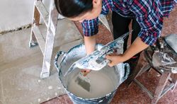Female builder working picking plaster with spatula