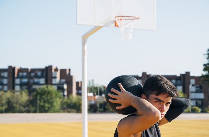 Young man playing on basketball court outdoor.