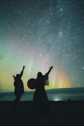 People dancing near sky in stars and polar lights at night