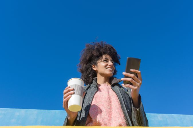 Black woman with afro hair leaning against brightly colored wall