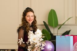 Girl holding flowers and smiling at birthday celebration.