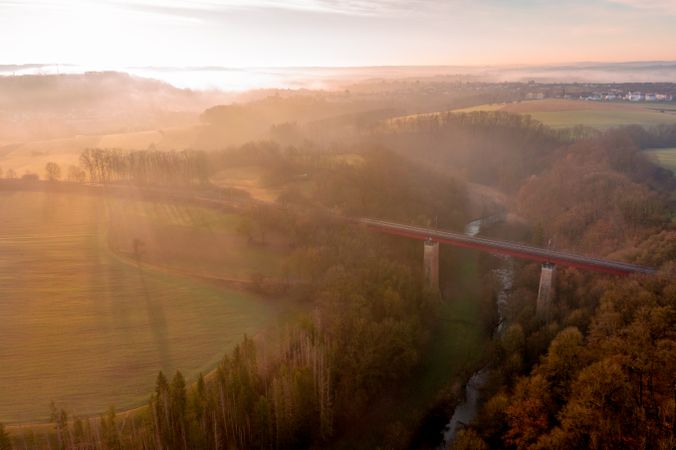 Drone aerial view of a railway bridge crossing the river in nature at sunrise on a winter morning