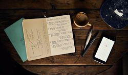 Rustic desk with a journal, pen, coffee and open smart phone