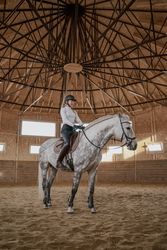 Rider riding dapple gray horse in round arena