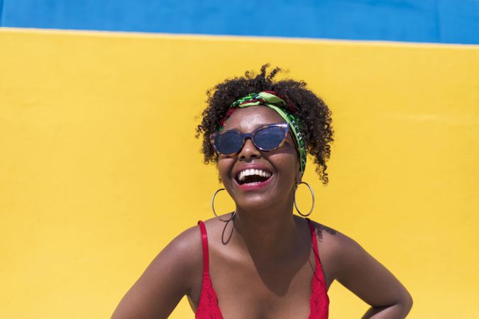 Portrait of Black woman smiling and looking at camera against yellow wall