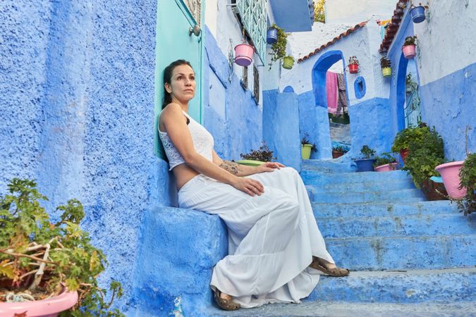 Pensive woman sitting on steps between ancient buildings