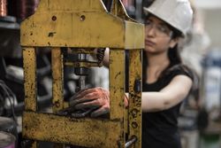 Woman working with heavy machine indoor