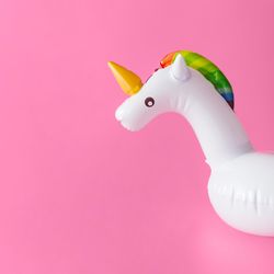 Inflatable unicorn pool toy on pastel pink background