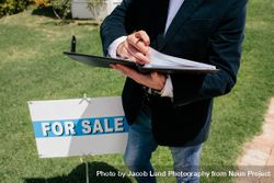 Real estate agent standing by signboard bGRAwx