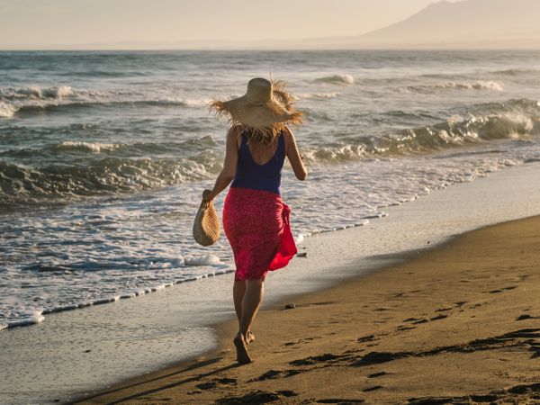 Woman in hat and running along seaside
