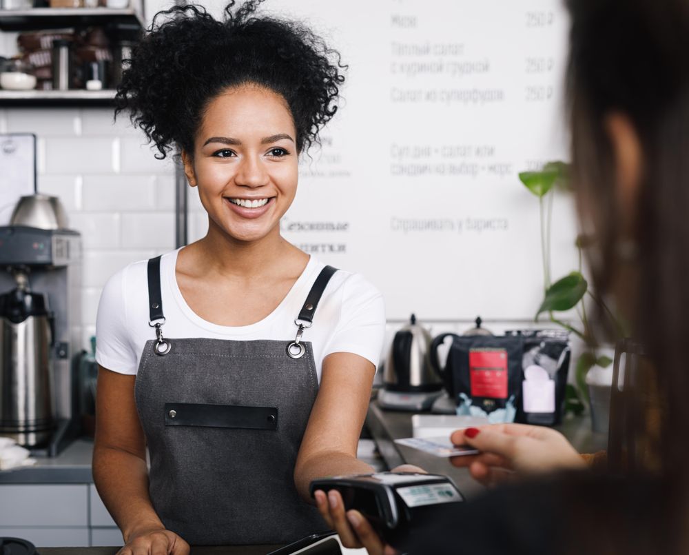 Barista taking payment from customer in coffee shop