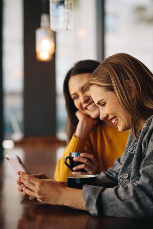 Young women sitting at cafe and using phone