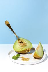 Sliced small melon on plate with spoon and fork