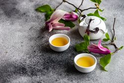 Magnolia flowers with green tea and teapot