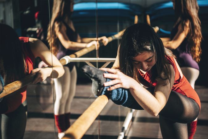 Concentrated ballet dancers training with barre in front of mirror in studio.