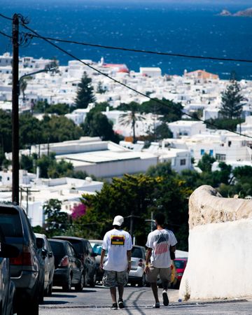 Back view of two men walking on street of Mykonos Island in Greece