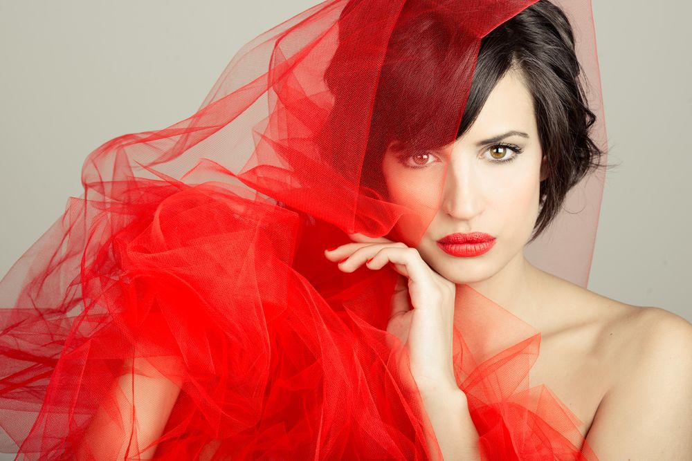 Female model draped in red mesh fabric