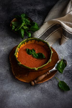 Traditional tomato soup in green bowl on grey counter