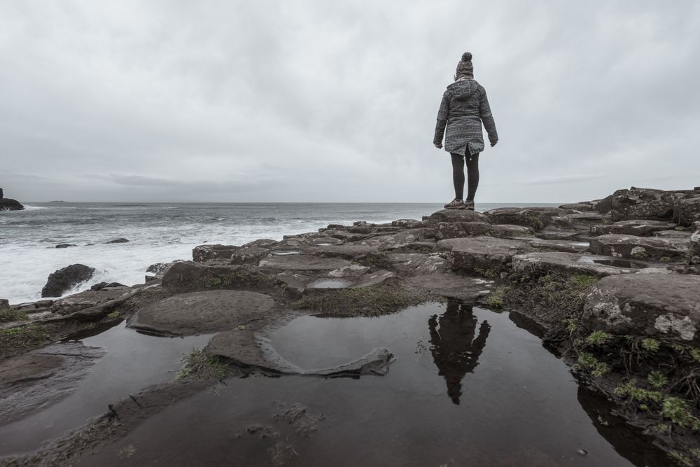 Female standing on cliff and contemplating
