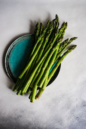 Loose raw asparagus on teal plate