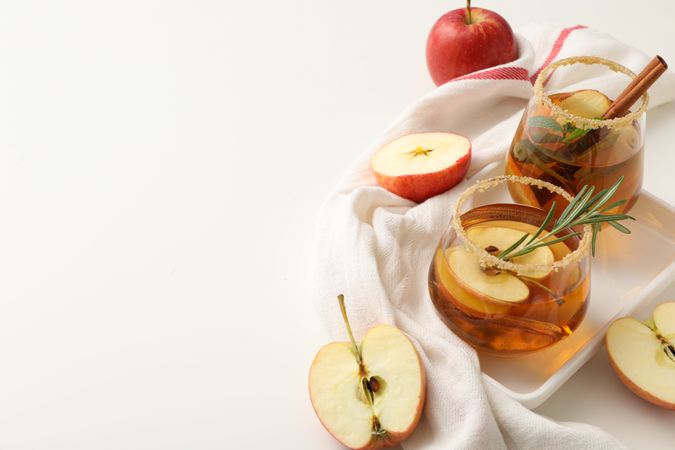 Glasses with apple cider and apples on towel, space for text