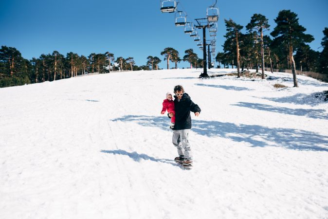 Man with daughter riding board on snow