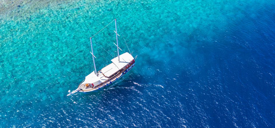 Aerial shot of boat in tropical blue waters, wide