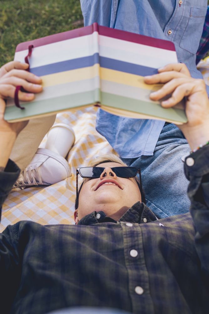 Young non-binary person relaxing in a park with a book