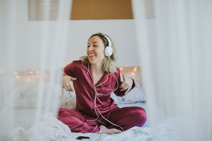 Woman with headphones listening to music in bed