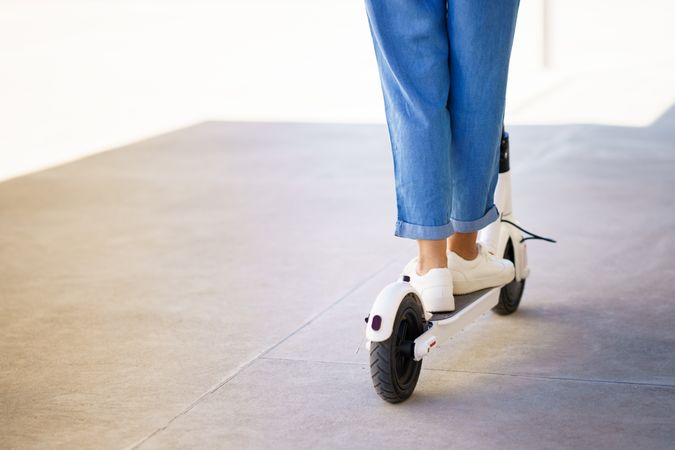 Close up of female legs riding around the city with an electric scooter
