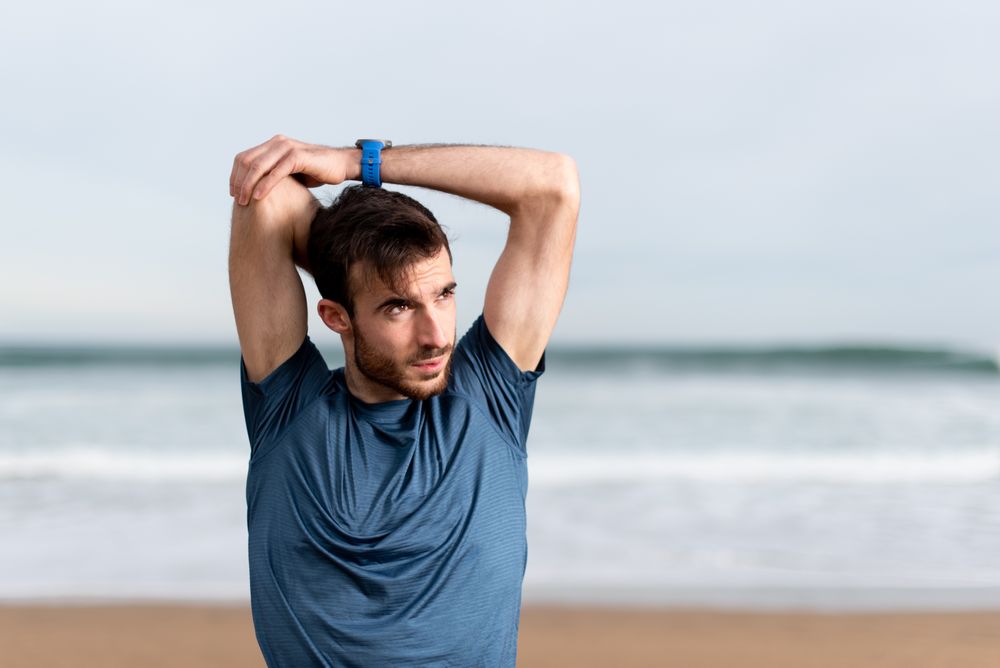 Sportsman warming up to train at beach
