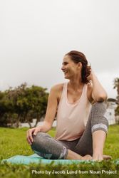 Portrait of a smiling woman sitting in park on a fitness mat 5zXQkb