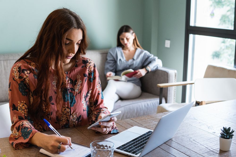 Focused woman taking notes and working on laptop