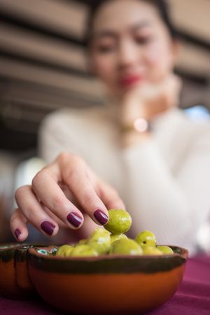 Asian woman eating olives in restaurant