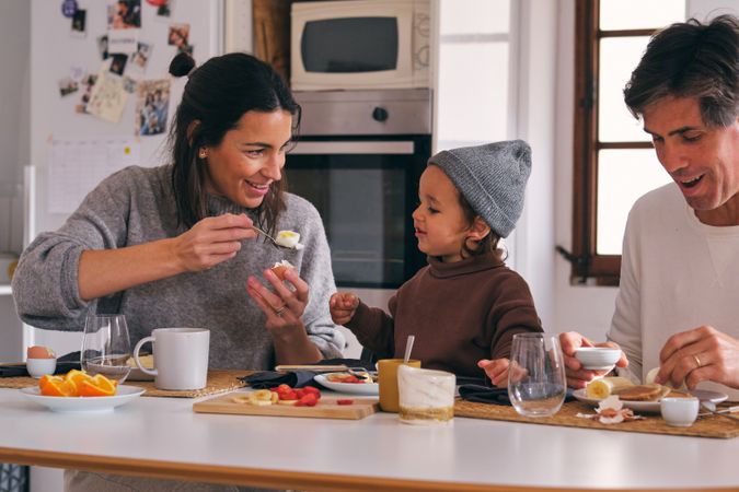 Crop family with little boy during breakfast at home
