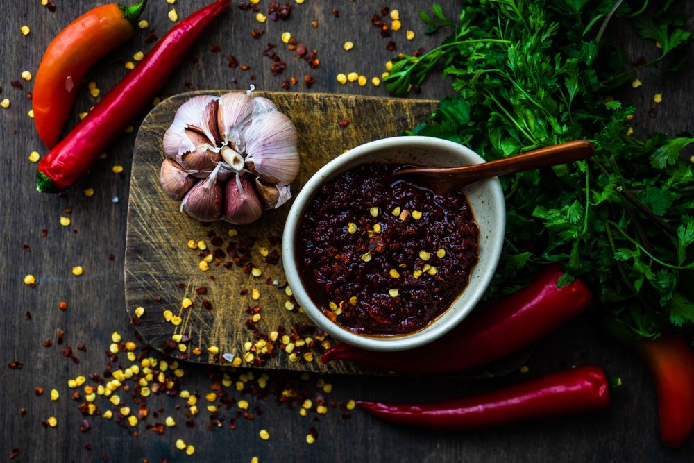 Rustic pot of traditional Georgian sauce Adjika with garlic bulb