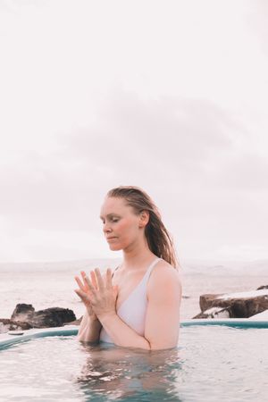 Woman sitting in pool near stones