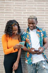 Young Black friends using smartphone in the street