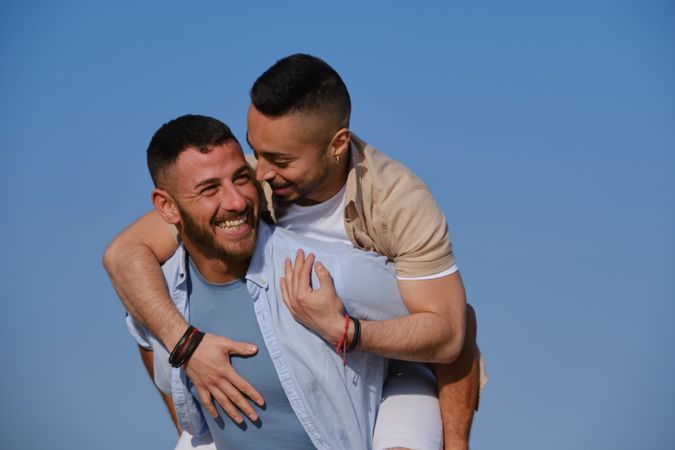 Happy gay couple playing piggyback
