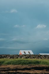 Small house in green filed under cloudy sky
