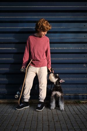 Little skater with dog resting on street