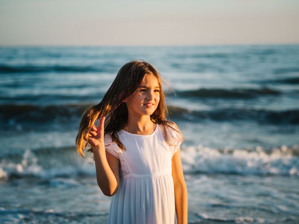 Adorable girl walking on seaside at sunset