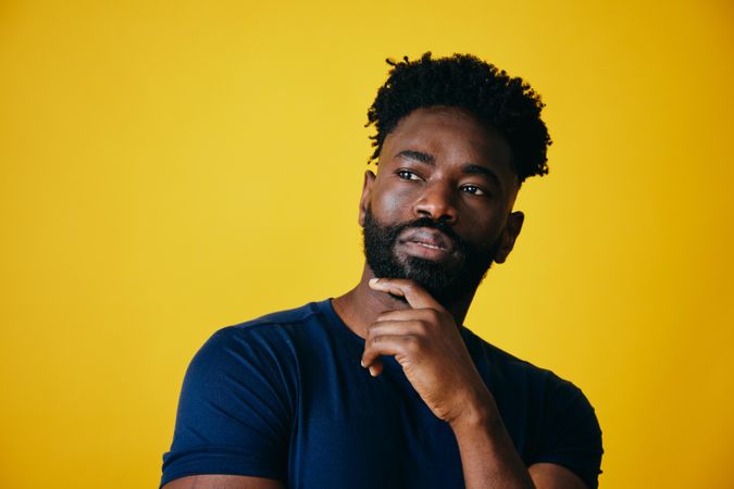 Portrait of Black man thinking about something on yellow background