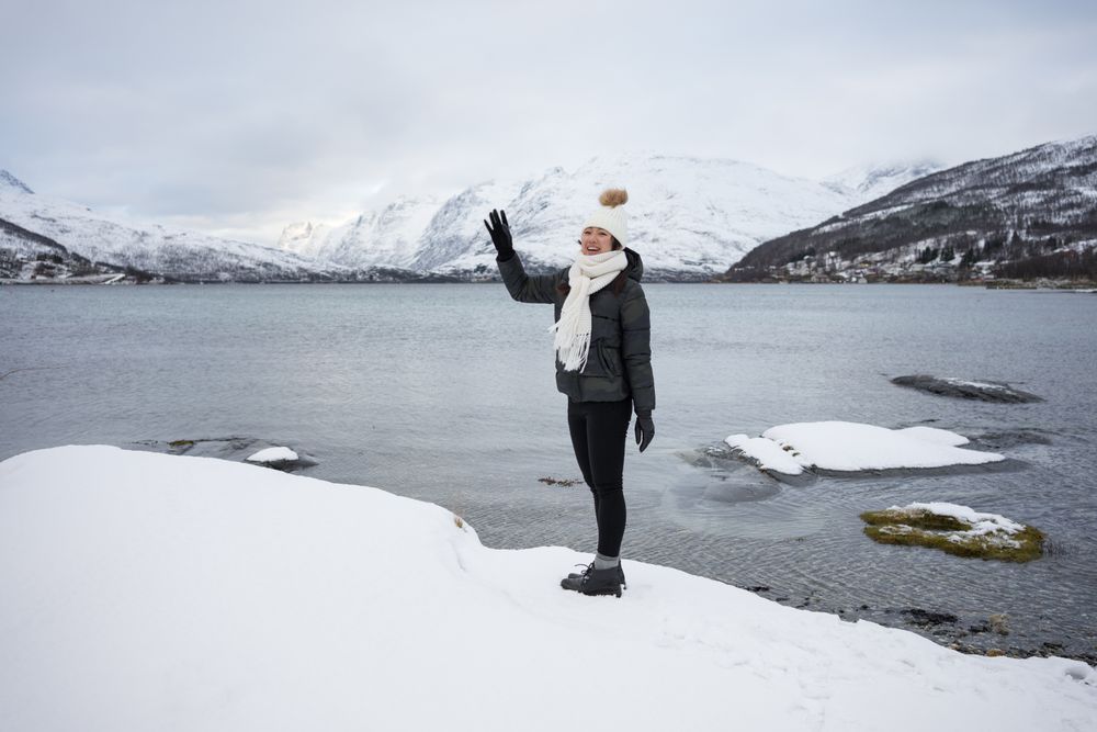 Young asian woman on pond shore against highland in winter