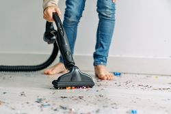 Child collecting festive confetti with vacuum cleaner